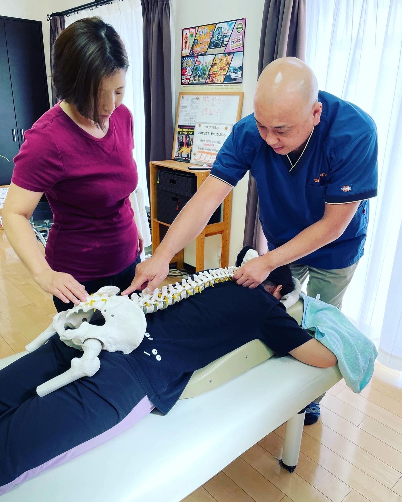 骨模型を使って背骨や骨盤の構造を確認しながら学ぶ様子